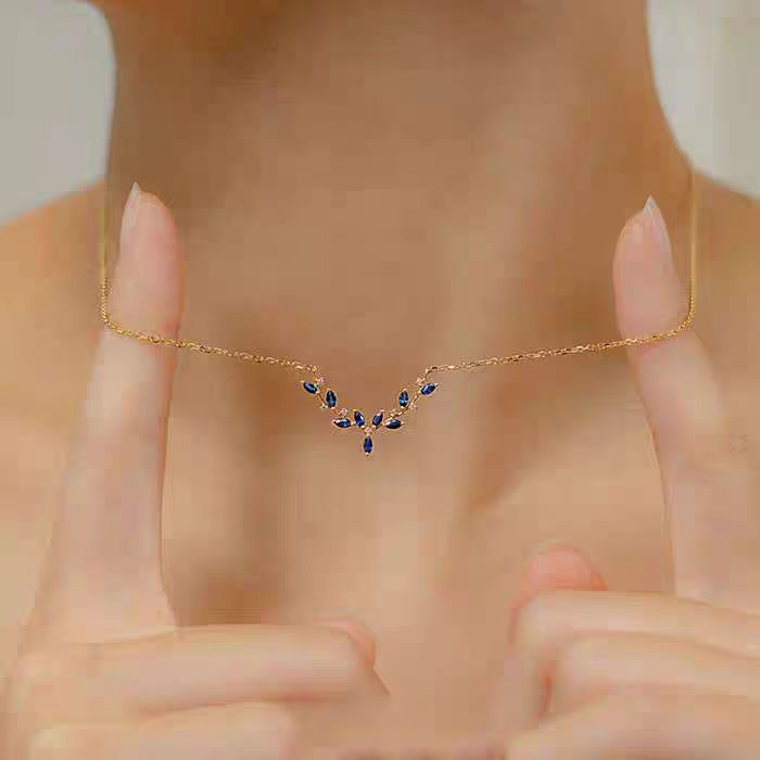 A delicate gold double-strand bracelet with a small flower charm and a star-shaped crystal accent, shown worn on a person's wrist with their hand resting behind it.