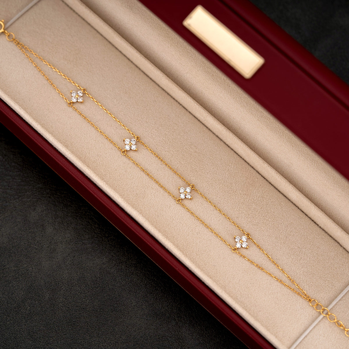 Dainty gold layered chain bracelet with zircon four-petal clover charms.