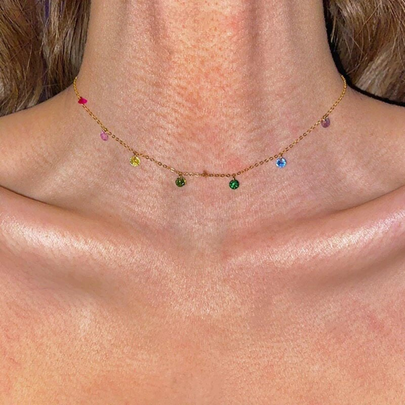 A delicate gold chain necklace featuring a butterfly pendant with blue and white enamel details, displayed on a light lavender background.