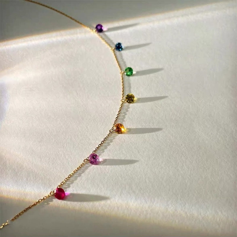 A delicate gold double-strand bracelet with a small flower charm and a star-shaped crystal accent, shown worn on a person's wrist with their hand resting behind it.
